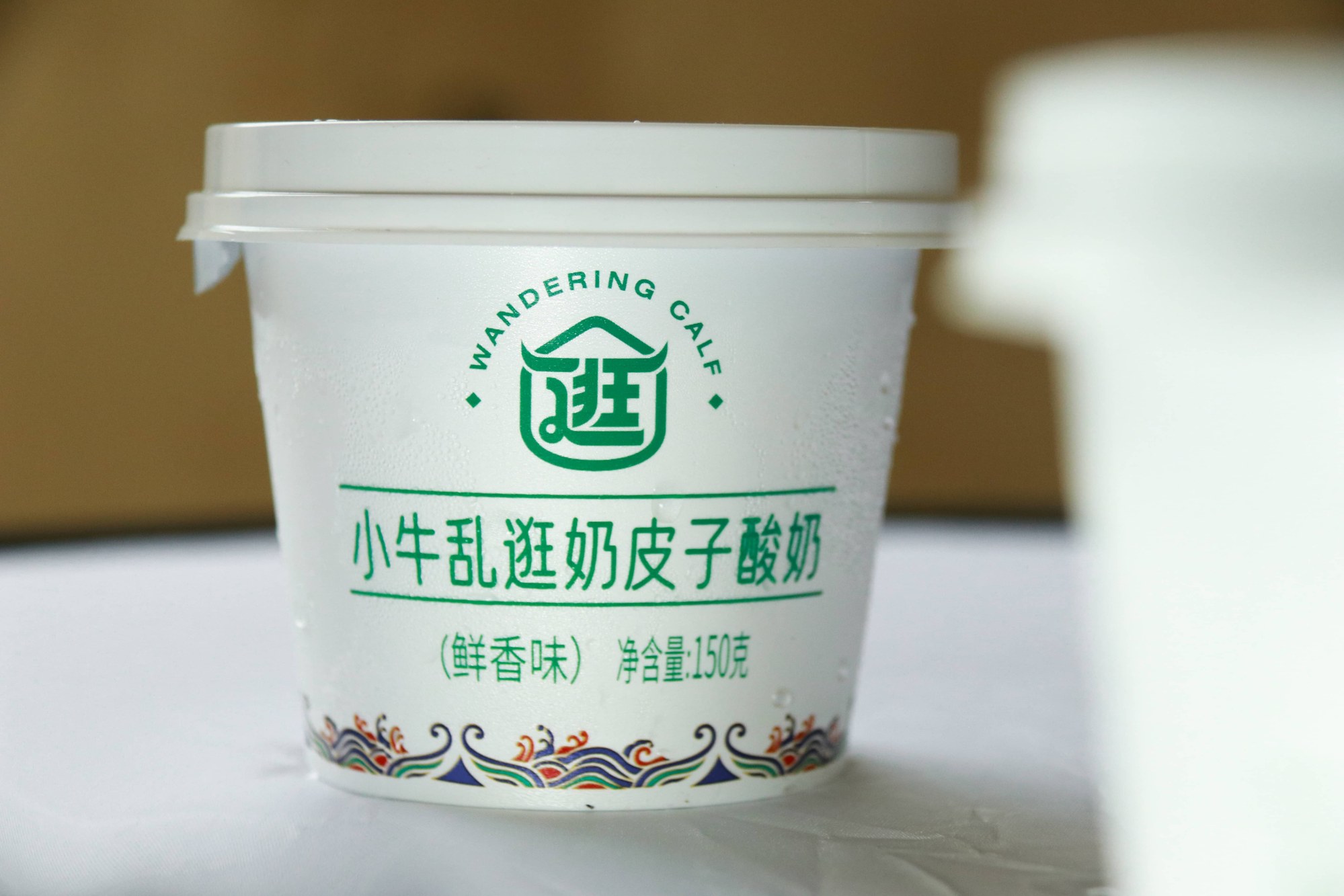 图注：小牛乱逛奶皮子酸奶，净含量 150 克，杯身印有"WANDERING CALF"标识。