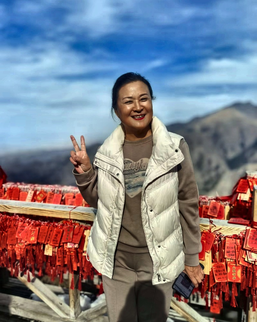 山口，她在挂满红牌的木栏前笑着。