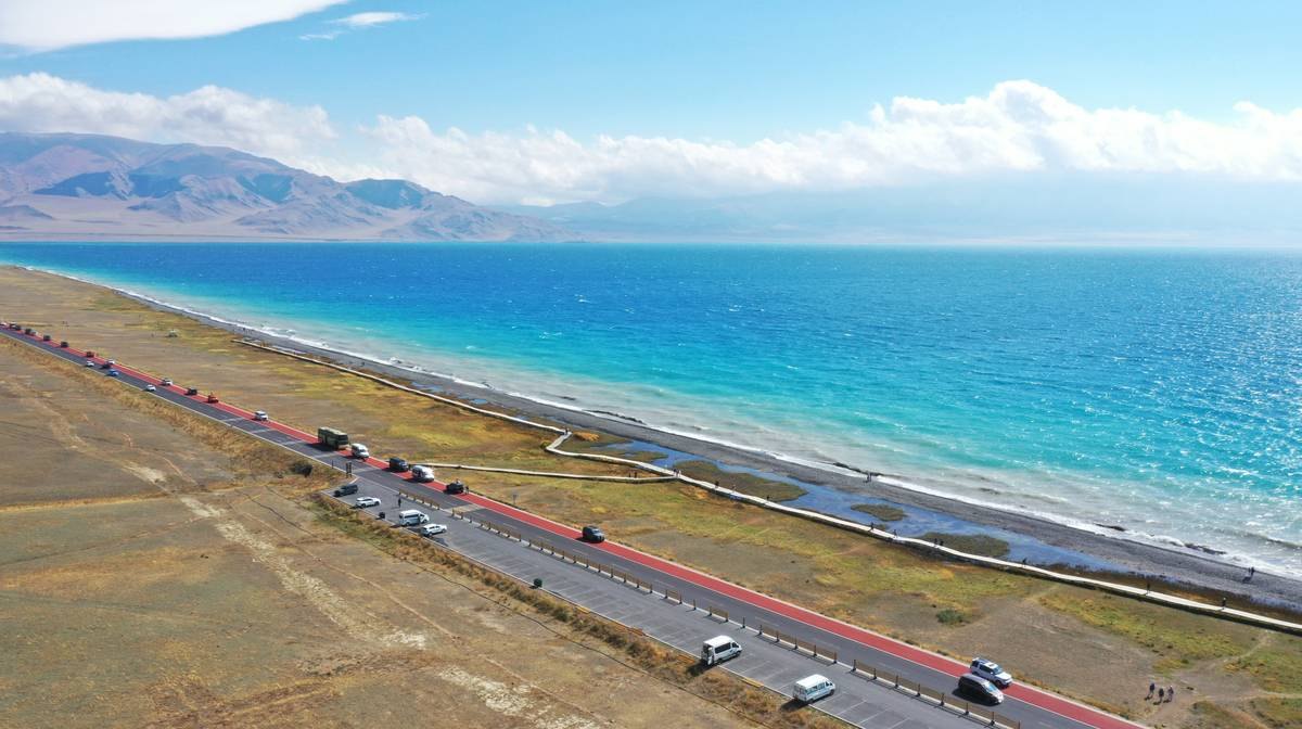 赛里木湖环湖公路航拍，蓝色湖面与远处的天山山脉