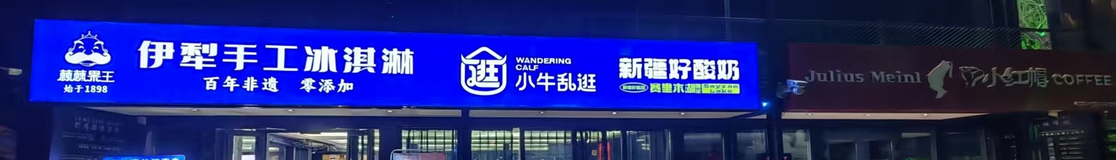 乌鲁木齐野马国际，一块蓝底招牌分三格：伊犁手工冰淇淋、小牛乱逛、新疆好酸奶
