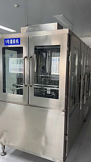 1 号灌装机。机身标牌写着"1号灌装机"，玻璃门内是灌装机构与输送链。