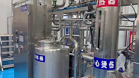 杀菌与换热系统区域。板式换热器与管道阀门密集分布，每段管路都挂着标识牌。